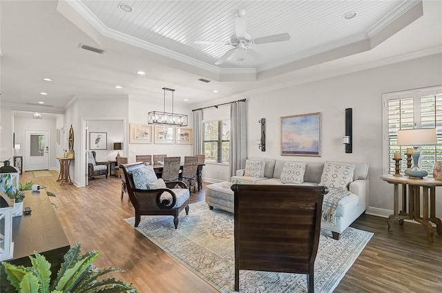 living area featuring a tray ceiling, visible vents, and wood finished floors