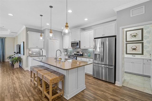 kitchen featuring visible vents, appliances with stainless steel finishes, ornamental molding, white cabinetry, and a sink