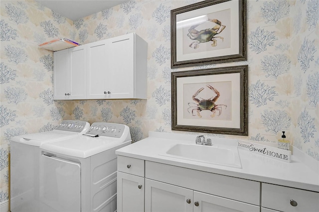 washroom with washer and dryer, cabinet space, a sink, and wallpapered walls