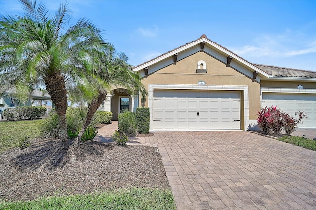 ranch-style home featuring a garage, decorative driveway, and stucco siding