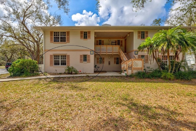 view of front facade with stairs, a front lawn, and a patio