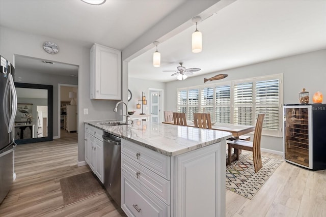 929 The Rialto, Venice, FL 34285 - kitchen featuring stainless steel appliances, light wood-style floors, white cabinets, a sink, and beverage cooler
