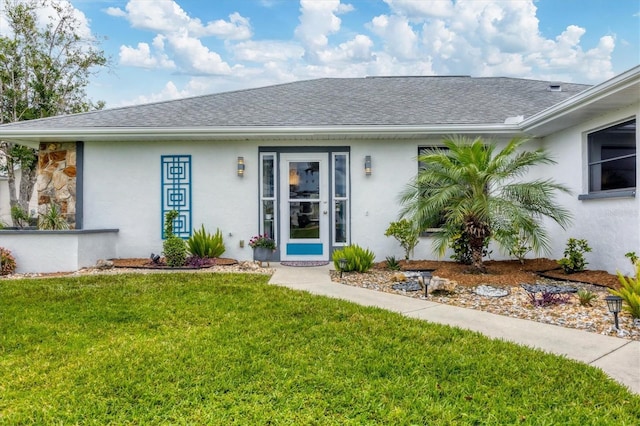 doorway to property featuring a shingled roof, a lawn, and stucco siding