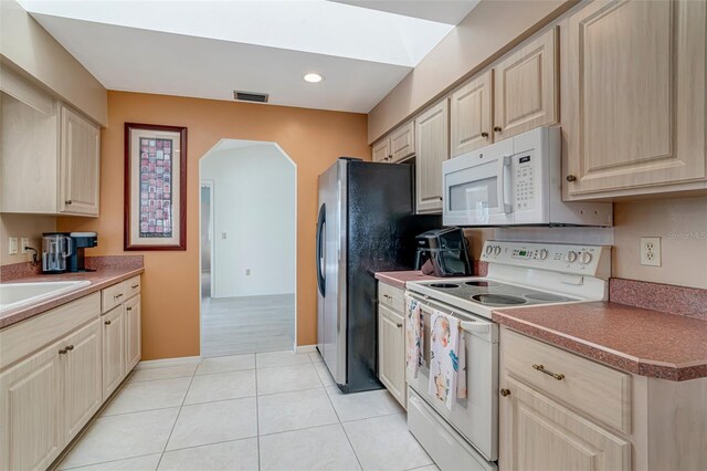 5875 Jackson, Venice, FL 34293 - kitchen with arched walkways, light tile patterned floors, visible vents, light brown cabinetry, and white appliances