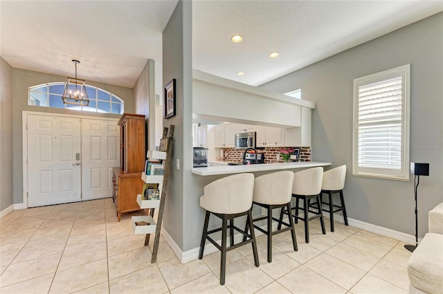 entryway with light tile patterned flooring, a chandelier, sink, and a textured ceiling