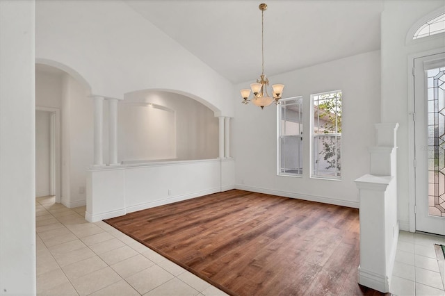 unfurnished dining area with a healthy amount of sunlight, a notable chandelier, baseboards, and tile patterned floors