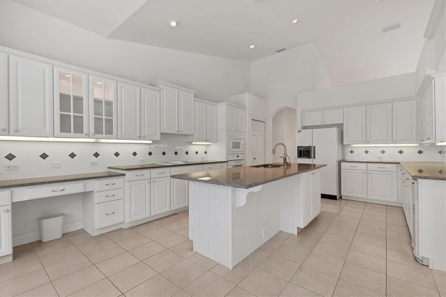 kitchen with white appliances, white cabinetry, a sink, and light tile patterned floors