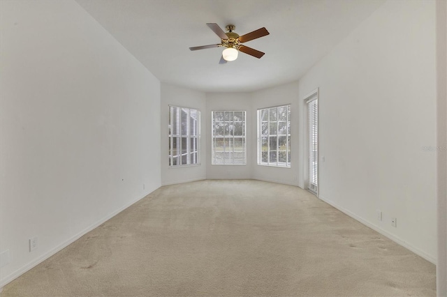 empty room featuring ceiling fan, baseboards, and light colored carpet
