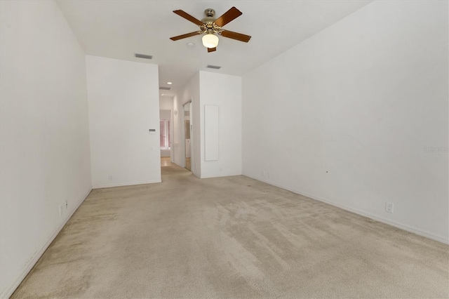 spare room with light carpet, visible vents, and a ceiling fan