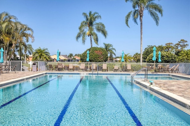 community pool with a patio area and fence