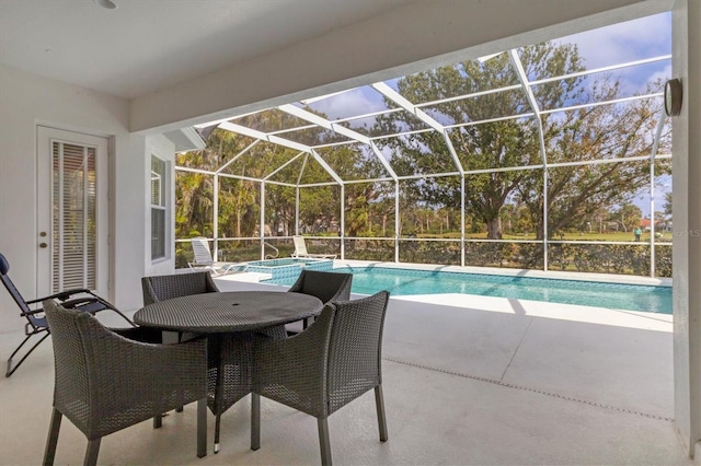 view of swimming pool with a patio, outdoor dining space, a pool with connected hot tub, and glass enclosure