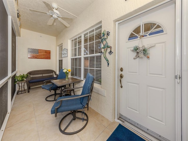 entrance to property featuring ceiling fan and stucco siding