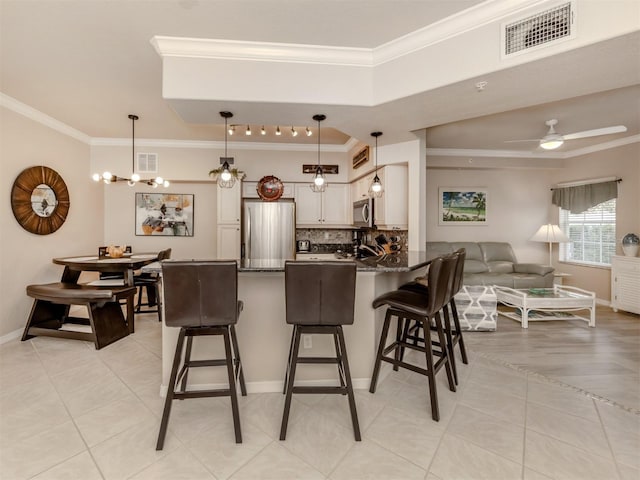 kitchen featuring a breakfast bar, visible vents, white cabinets, appliances with stainless steel finishes, and decorative light fixtures