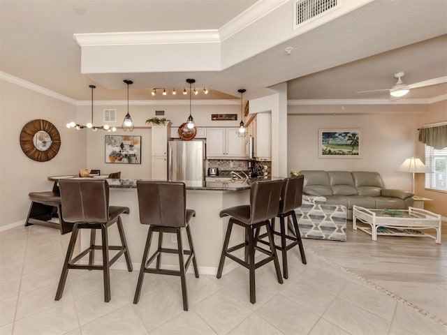 kitchen with a breakfast bar area, stainless steel appliances, hanging light fixtures, dark stone countertops, and crown molding