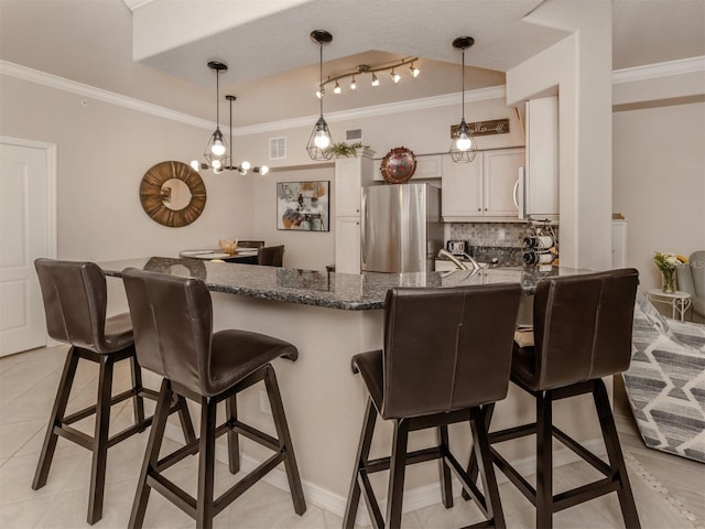 interior space with hanging light fixtures, crown molding, backsplash, and freestanding refrigerator