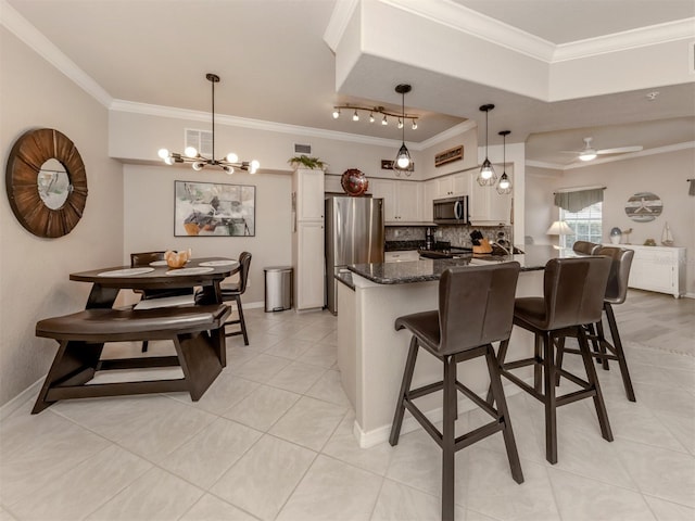 kitchen with pendant lighting, crown molding, appliances with stainless steel finishes, white cabinets, and a kitchen breakfast bar