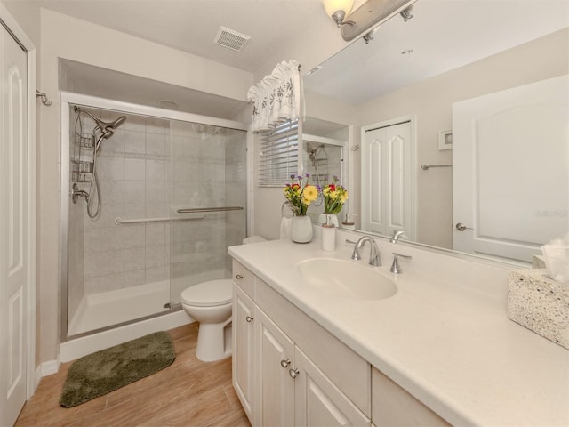 full bathroom featuring a stall shower, visible vents, wood finished floors, vanity, and a closet