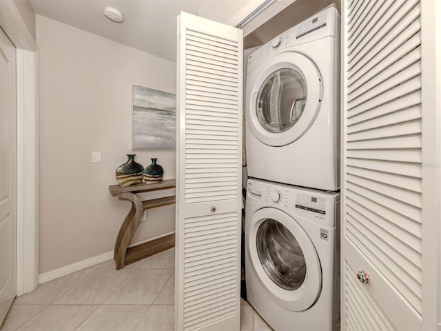 laundry room featuring light tile patterned floors, laundry area, baseboards, and stacked washer / drying machine