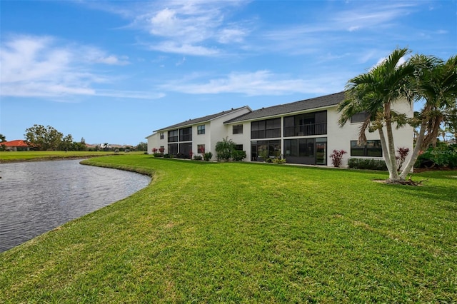 back of house with a water view and a lawn