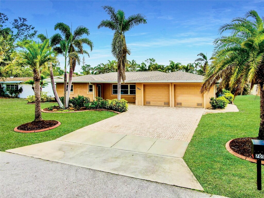 ranch-style house with a garage, decorative driveway, a front yard, and stucco siding