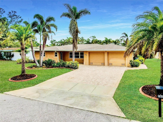 ranch-style house with a garage, decorative driveway, a front yard, and stucco siding