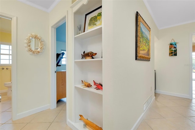 hallway with baseboards, crown molding, and light tile patterned flooring