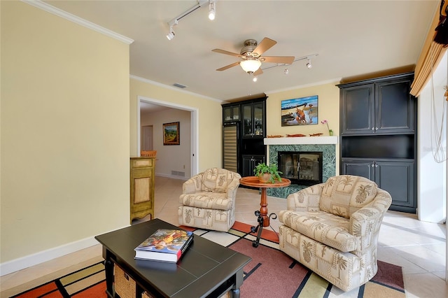 living room featuring light tile patterned floors, a ceiling fan, visible vents, a glass covered fireplace, and crown molding