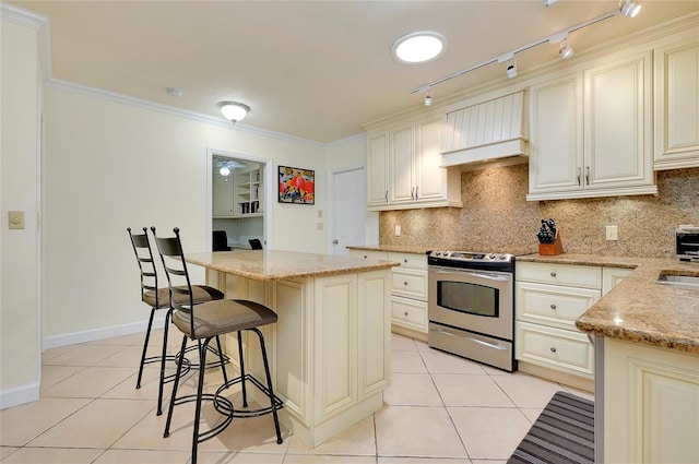 kitchen featuring stainless steel range with electric stovetop, cream cabinets, light stone counters, and a center island