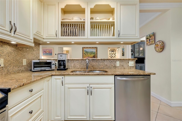 kitchen with light tile patterned floors, light stone counters, a toaster, a sink, and dishwasher