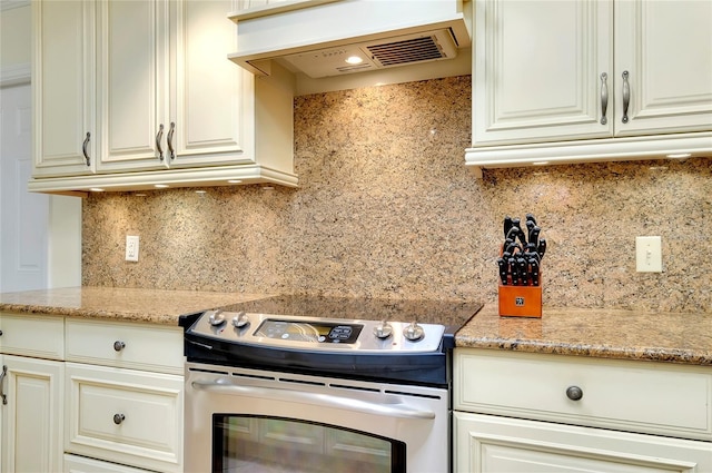 kitchen with premium range hood, electric range, decorative backsplash, and light stone countertops