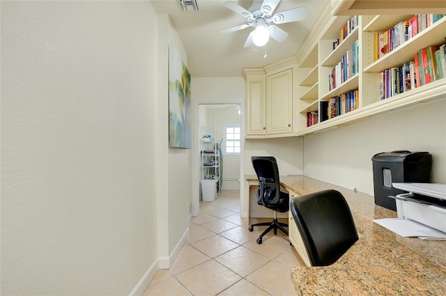 home office with light tile patterned floors, ceiling fan, visible vents, baseboards, and built in desk