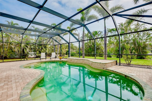 outdoor pool featuring glass enclosure and a patio