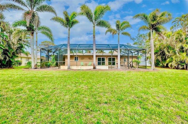 rear view of house featuring glass enclosure and a lawn