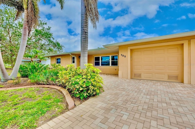 view of front of house with a garage, decorative driveway, and stucco siding