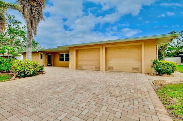 single story home featuring decorative driveway, an attached garage, and stucco siding