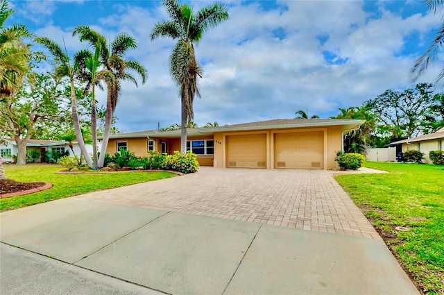 ranch-style home featuring an attached garage, a front lawn, decorative driveway, and stucco siding