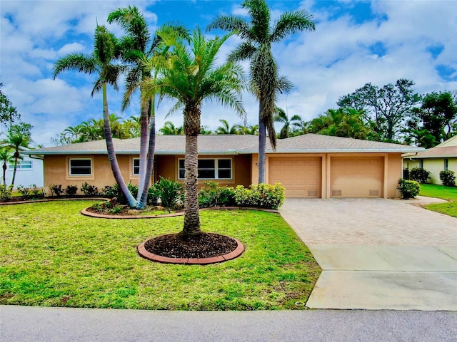 ranch-style house featuring a garage, decorative driveway, a front yard, and stucco siding