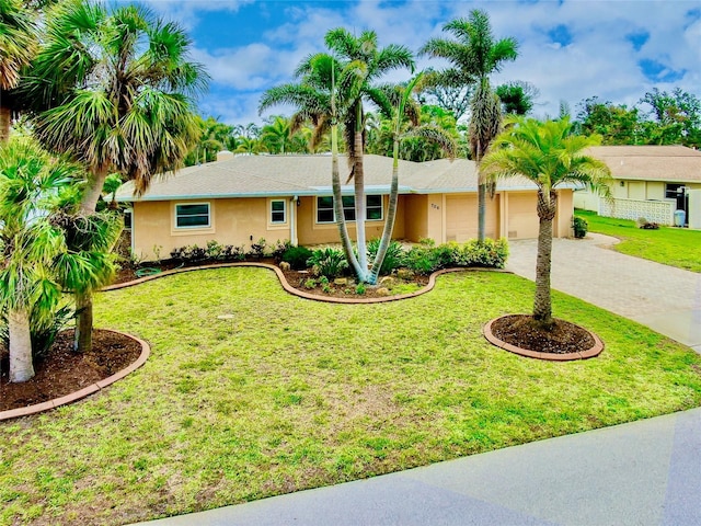 ranch-style house with a garage, a front yard, decorative driveway, and stucco siding