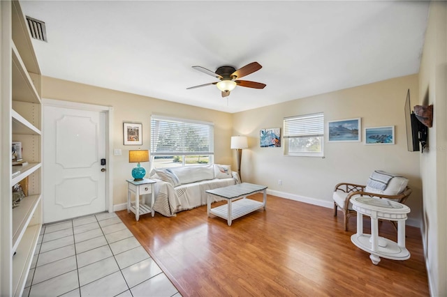 living area featuring ceiling fan, light wood-style flooring, visible vents, and baseboards