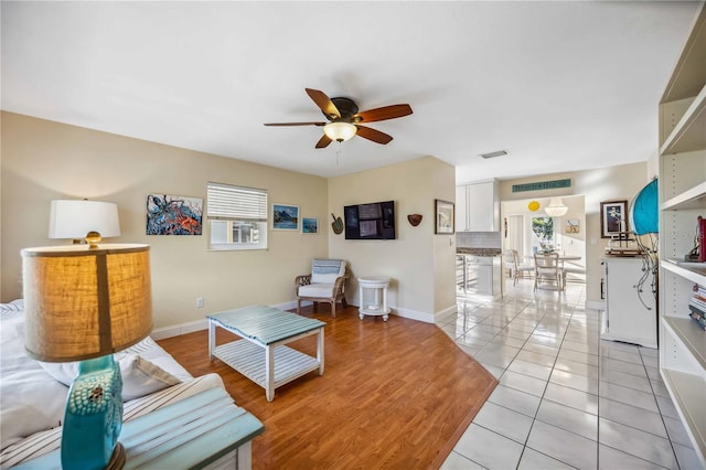 living area with light tile patterned floors, plenty of natural light, visible vents, and a ceiling fan