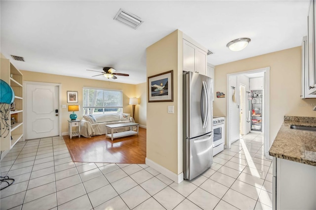 kitchen with light tile patterned floors, visible vents, white range with electric cooktop, and freestanding refrigerator