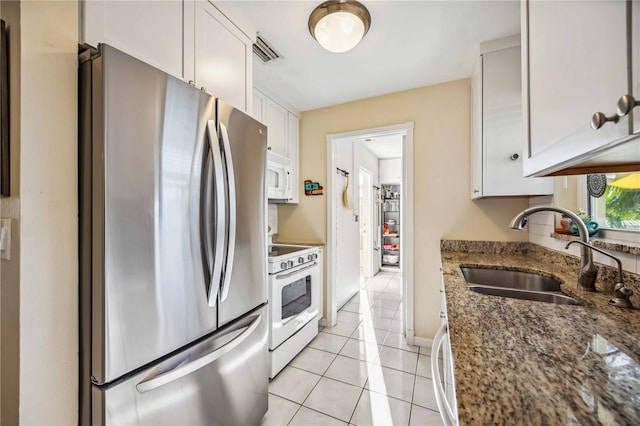 kitchen featuring light tile patterned floors, visible vents, white cabinets, a sink, and white appliances