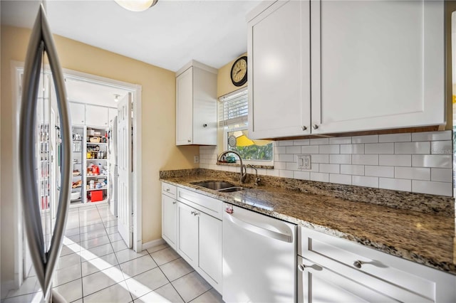 kitchen featuring decorative backsplash, light tile patterned flooring, a sink, dishwasher, and stainless steel refrigerator