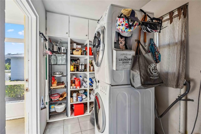 clothes washing area with light tile patterned floors, laundry area, and stacked washer and dryer