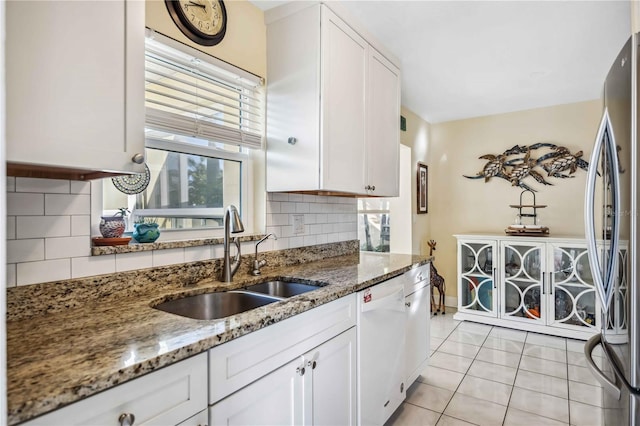 kitchen featuring freestanding refrigerator, white cabinets, dishwasher, and a sink