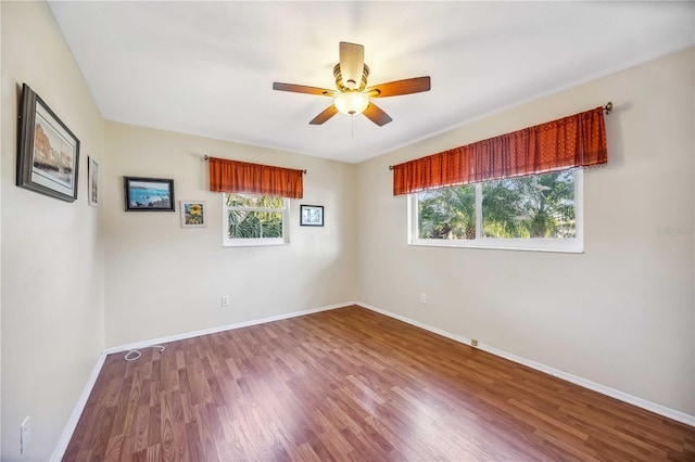 spare room featuring ceiling fan, plenty of natural light, baseboards, and wood finished floors