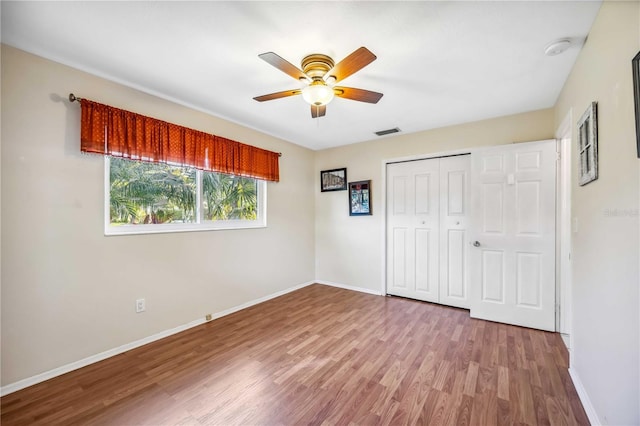 unfurnished bedroom featuring ceiling fan, a closet, wood finished floors, and baseboards