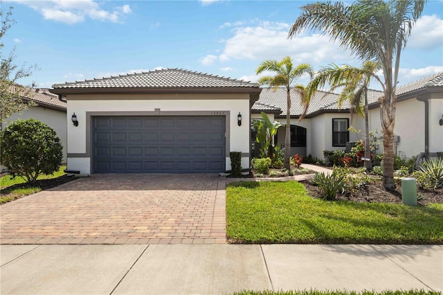 view of front of property featuring a garage, decorative driveway, a tile roof, and stucco siding