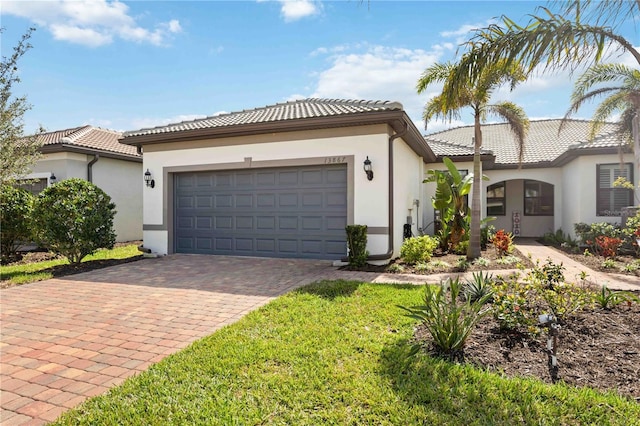 mediterranean / spanish-style house featuring an attached garage, a tiled roof, decorative driveway, stucco siding, and a front yard