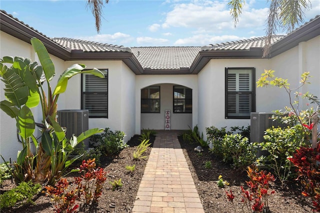 13867 Vadini St, Venice, FL 34293 - view of exterior entry featuring central AC unit, stucco siding, and a tiled roof